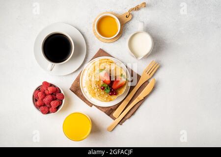 Frühstückstisch mit Pfannkuchen, frischen Beeren und Kaffee mit Milch. Draufsicht. Stockfoto