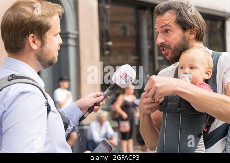 Cambridge Circus, London, Großbritannien. August 2021. Die Demonstranten vom Aussterbungsaufstand sitzen am Cambridge Circus und blockieren die Charing Cross-Straße auf dem Weg zum Trafalgar Square. LBC News interviewt einen Mann mit Kleinkind . Quelle: Xiu Bao/Alamy Live News Stockfoto