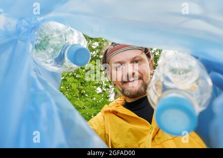 Freiwillige sammeln Abfall Abholung Müll Plastikflasche in Müllbeutel. Mülltüte aus Plastik abholen. Freiwillige Reinigung Park Blick von innen ein Stockfoto