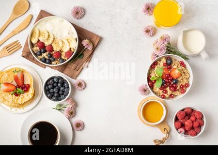 Ein Tisch für ein gesundes Frühstück mit Pfannkuchen, Müsli, frischen Beeren, Kaffee mit Milch und Orangensaft. Draufsicht. Stockfoto