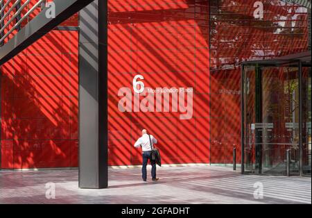 Ein Geschäftsmann in weißem Hemd blickt auf seine Uhr vor dem Betteingang von 6 More London Place. London - 24. August 2021 Stockfoto