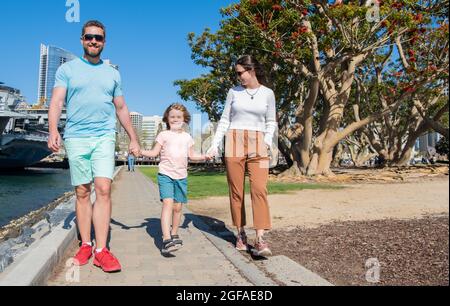 Glückliche junge Familie, die im Park mit Sohn, Familie läuft Stockfoto