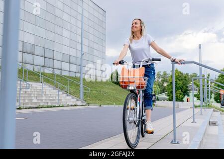 Schöne und fröhliche Frau genießen Radtour in sonnigen städtischen Outdoor-Freizeitaktivitäten in der Stadt. Stockfoto