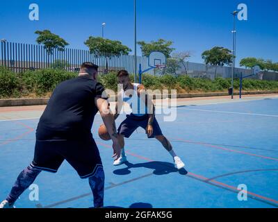 Sportlich attraktive spanische Basketballspieler trainieren auf einem Basketballplatz Stockfoto