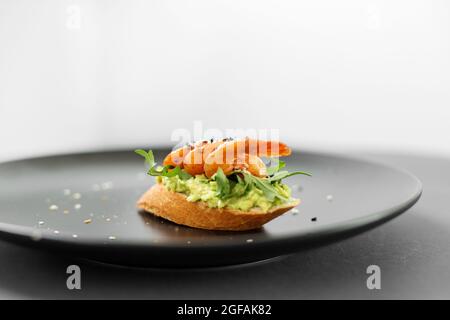 Bruschetta mit Avocado und Meeresfrüchten, Garnelen-Sandwich auf einem Teller vom Buffet Stockfoto