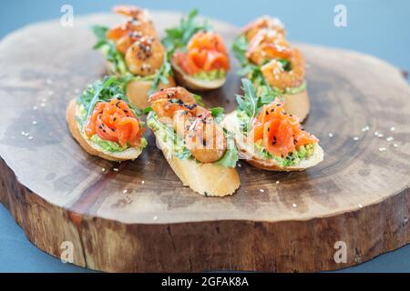 Bruschetta mit Avocado und Lachs, Shrimp Sandwich auf einem Buffetteller auf einem Holzständer Stockfoto
