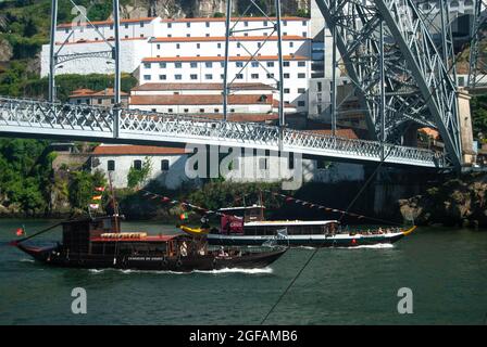 Porto, Portugal - 6. Juni 2021: Touristische Boote, die unter der Dom Luis I Brücke vorbeifahren, kommen von der Tour entlang des Douro Flusses zurück
