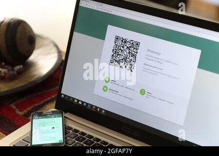 WhatsApp-Webverbindungsseite wurde in einem Laptop geöffnet. QR-Code auf dem Bildschirm und Handy über die Tastatur. Stockfoto