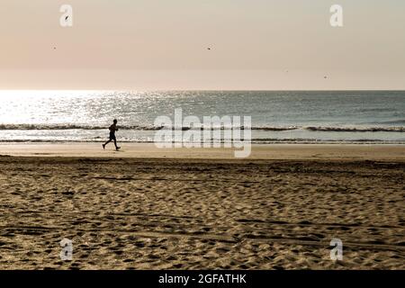 Mann, der an einem sonnigen Sommermorgen zum Strand läuft. Stockfoto