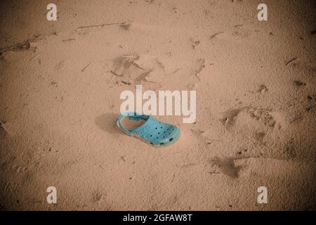 Türkisfarbener klassischer Krokenglog, der auf Sanddünen aufgegeben wurde. Der 'Digital aqua'-farbige Schuh ist teilweise im Sand vergraben. Stockfoto