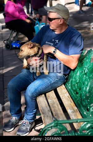 Ein Mann entspannt sich mit seinem Hund auf einer Bank in einem öffentlichen Park in Santa Fe, New Mexico. Stockfoto