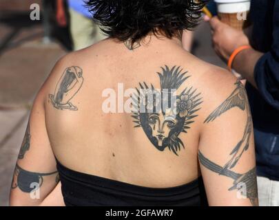 Eine junge Frau mit einem Herz-Jesu-Tattoo auf dem Rücken besucht eine Kunstausstellung im Freien in Santa Fe, New Mexico. Stockfoto