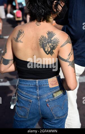 Eine junge Frau mit einem Herz-Jesu-Tattoo auf dem Rücken besucht eine Kunstausstellung im Freien in Santa Fe, New Mexico. Stockfoto