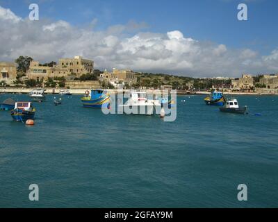 BIRZEBBUGA, MALTA - 30. März 2014: Die bunten kleinen Fischerboote, die mit Bojen in der St. George's Bay in Birzebbuga, Malta, festgemacht sind. Stockfoto