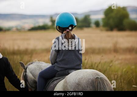 5-jähriges Mädchen, das auf einem Pferd reitet, in einem hipico-Club Stockfoto