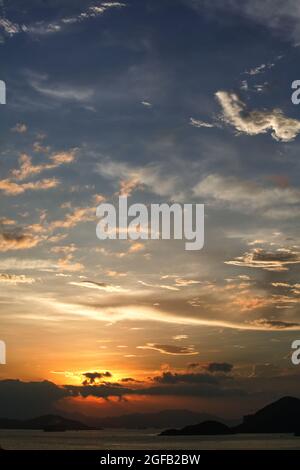 Schöner Blick auf das Meer, das unter dem Sonnenuntergang im wolkigen blauen Himmel schimmert Stockfoto
