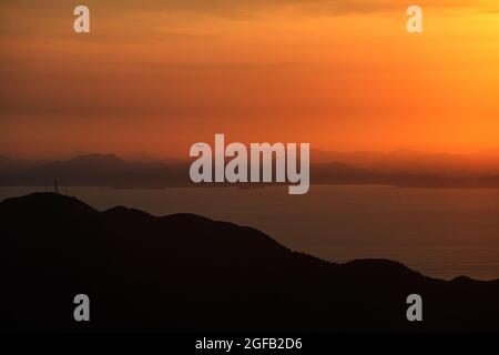 Schöner Blick auf das Meer, das unter dem Sonnenuntergang im wolkigen Himmel schimmert Stockfoto