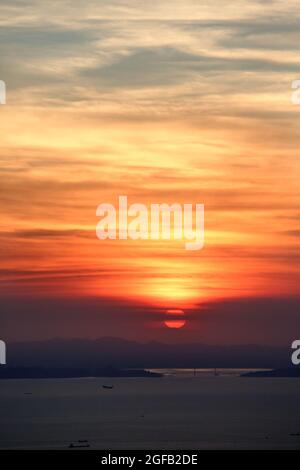 Schöner Blick auf das Meer, das unter dem Sonnenuntergang im wolkigen Himmel schimmert Stockfoto