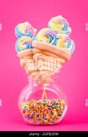 Bunte Eiscreme-förmige Lutscher auf einem leuchtend rosa Hintergrund Stockfoto
