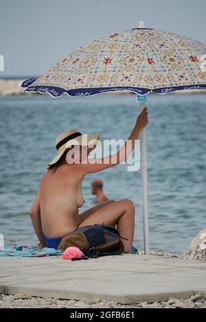 Sitzende Frau unter ihrem Sonnenschirm Stockfoto