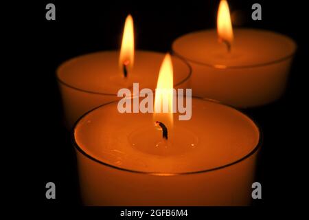 Kerzenflamme. Weiße Kerzen gesetzt. Brennende Kerzen im Dunkeln.Nahaufnahme Kerzenflamme. Stockfoto