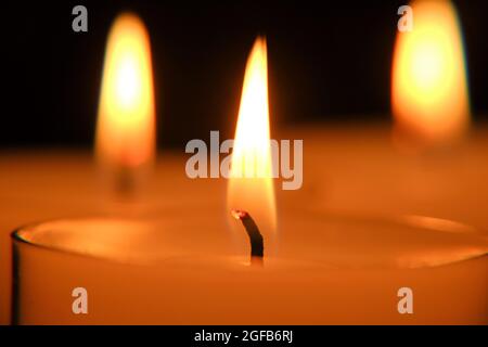 Kerzenflamme aus der Nähe. . Weiße Kerzen gesetzt. Brennende Kerzen im Dunkeln. Stockfoto