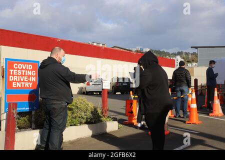 Wellington, Neuseeland, 25. August 2021. Ein Mann zeigt einem Gesundheitshelfer seinen Ausweis, der in einem Testzentrum in Wellington, Neuseeland, Personen eincheckt, das derzeit aufgrund eines Ausbruchs der Deltavariante in einer strengen Stufe 4 gesperrt ist. Quelle: Lynn Grieveson/Alamy Live News Stockfoto