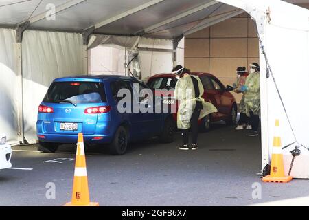 Wellington, Neuseeland, 25. August 2021. Gesundheitshelfer mit Gesichtsschutz und PSA führen Covid-19-Tests in einem Drive-Through-Testzentrum im Te Papa Museum in Wellington, Neuseeland, durch, das derzeit aufgrund eines Ausbruchs der Delta-Variante in einer strengen Stufe-4-Sperre ist. Quelle: Lynn Grieveson/Alamy Live News Stockfoto