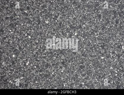 Nahaufnahme von dunkelgrauem Granit mit kleinen weißen Einschlüssen. Hintergrund, Muster, Textur. Stockfoto