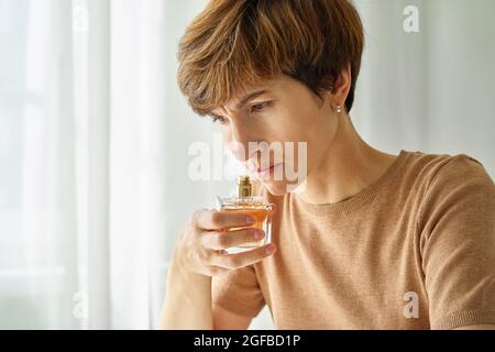 Weibliche schnüffende Parfümflasche, Selbstkontrolle auf Vorhandensein von Covid. Lang anhaltendes Covid19-Beschwerden Stockfoto