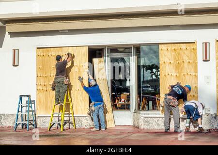 Miami Beach, Florida, TGI Friday's Restaurant Business, der sich dem Unruh Irma nähert, Sperrholz-Sperrholz-Einstiegsfenster Arbeiter, die Männer Leiter vorbereiten, Stockfoto