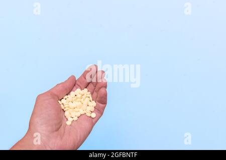 Hand mit einem Haufen gelber Pillen auf blauem Hintergrund, Platz kopieren. Gesundheitskonzept. Depressionen Medikamente, Psychische Gesundheit Stockfoto