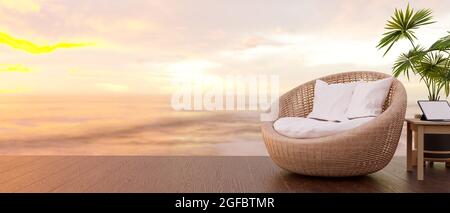 Sommerferien, Rattanstuhl, Strandkorb, tragbares Tablet auf dem Tisch, Platz auf Holzboden, Kokospalme und Sonnenuntergang über dem Meer in der Nähe Stockfoto