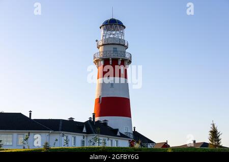 Leuchtturm in roten und weißen Farben an der Küste, am Flussufer oder am Seeufer. Leuchtturm Hotel in einem Fischerdorf. Reise- und Tourismuskonzept Stockfoto