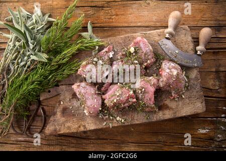 Zubereitung mit gehackten aromatischen mediterranen Kräutern aus rohen Kaninchenportionen Stockfoto