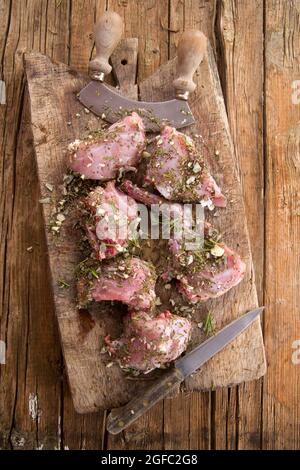 Zubereitung mit gehackten aromatischen mediterranen Kräutern aus rohen Kaninchenportionen Stockfoto