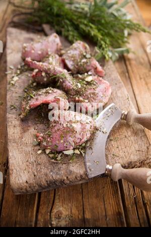 Zubereitung mit gehackten aromatischen mediterranen Kräutern aus rohen Kaninchenportionen Stockfoto