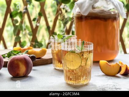 Hausgemachte Gärung. Kombucha-Tee leicht alkoholisches, leicht brausendes Getränk mit Pfirsich und Limette. Stockfoto