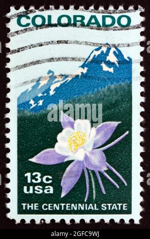 VEREINIGTE STAATEN von AMERIKA - UM 1977: Eine in den USA gedruckte Briefmarke zeigt Columbine und Rocky Mountains, 100 Jahre Staatlichkeit, um 1977 Stockfoto