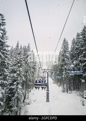 Wunderbare Winterszene mit Schneefall, während man mit der Seilbahn auf den Gipfel des Berges klettert. Skigebiet Bukovel in den ukrainischen Karpaten Stockfoto