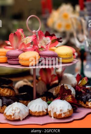 Bunte Makronen und leckere Kuchen auf einem Tablett. Frisches Gebäck auf einem Tablett. Vertikales Foto Stockfoto