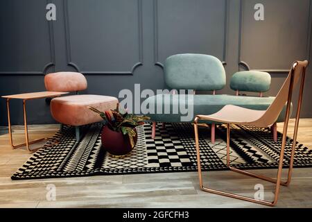 Moderne Inneneinrichtung mit komfortablem Sofa und Sessel. Wohnzimmer mit elegantem Couchtisch und stilvollem Teppich. Stockfoto
