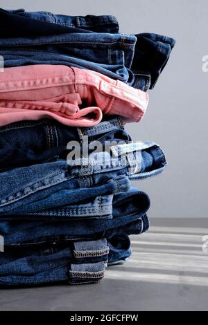 Ein Stapel blauer und pinker Jeans auf dem Hintergrund. Stockfoto