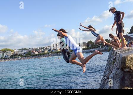 San Sebastian, Spanien. August 2021. Junge Leute tauchen in das Meerwasser und machen akrobatische Sprünge am Strand La Concha in San Sebastian.Jugendliche genießen diesen Sommer den Sprung von der Wand am Ende der Promenade von Playa de la Concha de San Sebastian neben dem Monte Igueldo mit spektakulären Sprüngen und ohne Die Gefahr, dass die Steinklippen für diese Art von Sprüngen bieten. Kredit: SOPA Images Limited/Alamy Live Nachrichten Stockfoto