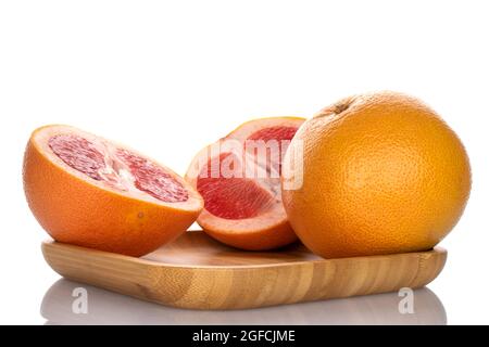 Eine ganze und zwei Hälften einer köstlichen reifen Grapefruit auf einem Bambustablett, Nahaufnahme, isoliert auf Weiß. Stockfoto