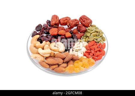 Gruppe von ganzen Körnern und getrockneten Früchten in einer Glasplatte isoliert auf weißem Hintergrund. Stockfoto