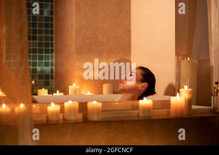 Schöne junge Frau, die sich in der Badewanne entspannen kann Stockfoto