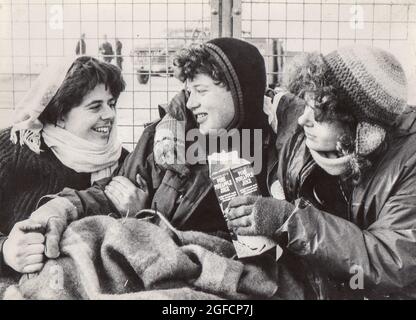 Frauen versammeln sich um den Umzäunungszaun im Greenham Common Womens Peace Camp während des Aktionstages „Embrace the Base“ vom 12. Bis 13. Dezember 1982. Stockfoto