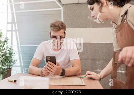 Typ mit Bart bestellt im Restaurant eine Kellnerin in Schutzmaske Stockfoto