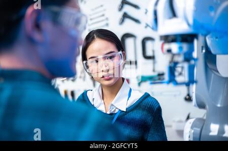 Kaukasische und asiatische Ingenieure Wartung Roboter Arm im Labor. Sie sind in einem High-Tech-Forschungslabor mit moderner Ausrüstung. Professionelle japanische D Stockfoto